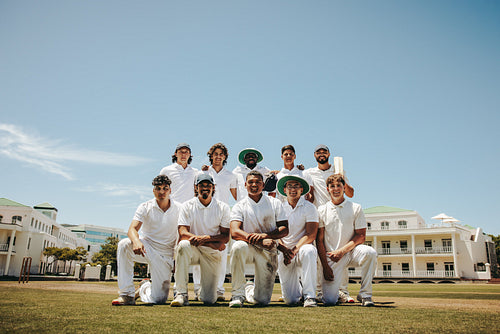 Cricket team poses together outdoors under a sunny blue sky