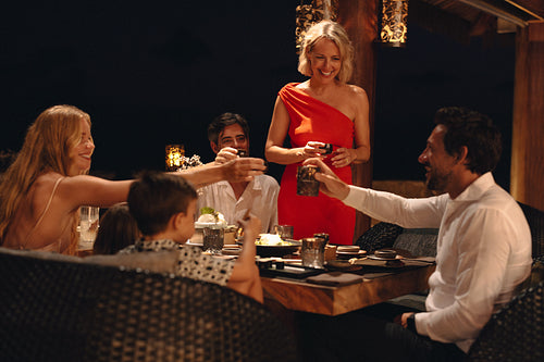 Family celebrating with toasts during a fine dining evening gathering at a resort