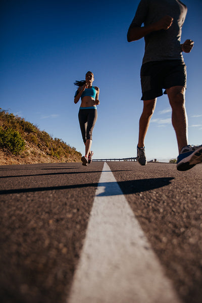Woman running on road with man in front