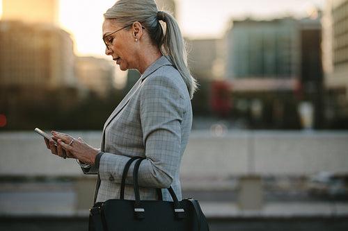 Businesswoman texting on phone while walking outdoor