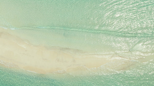 Aerial view of a pristine white sandbar surrounded by crystal clear turquoise ocean water and gentle waves