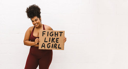 Pretty woman with "Fight like a girl" sign board