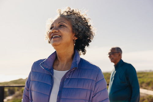 Carefree senior woman looking at a refreshing view on a foot bridge