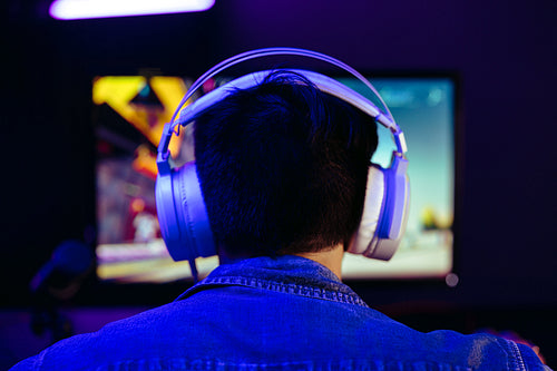 Gamer wearing headphones, live streaming his gameplay for his online subscribers