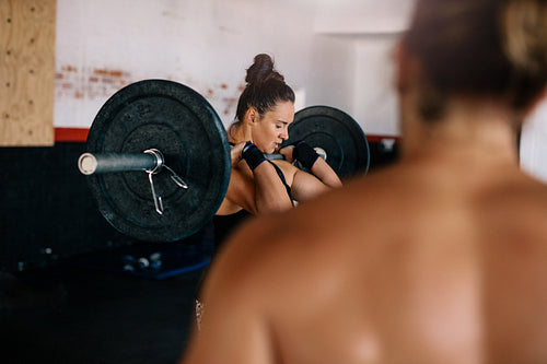 Female bodybuilder doing weightlifting exercise in gym