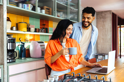 Couple enjoying coffee while working together in a cozy colorful kitchen