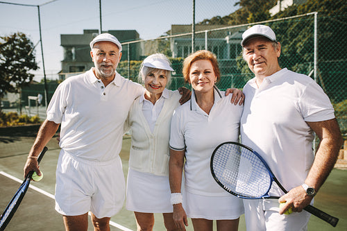 Senior men and women standing together on a tennis court