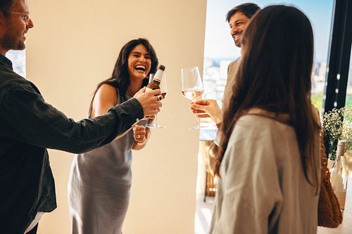 Friends toasting with drinks and enjoying a lighthearted moment at home