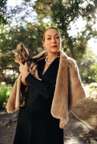 Middle aged posh woman looking at the camera while holding her puppy