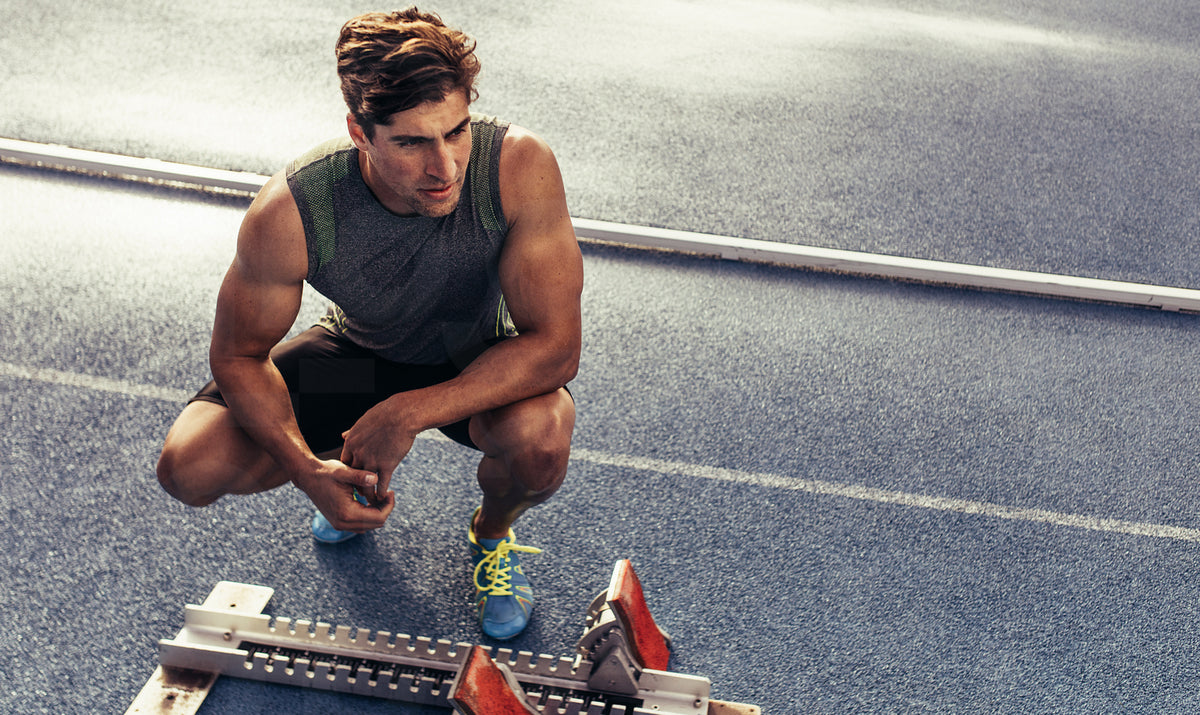 Sprinter sitting beside a starting block on running track – Jacob Lund ...