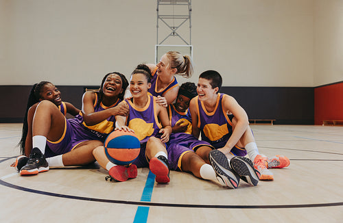 Young women athletes bonding on basketball court in team uniforms