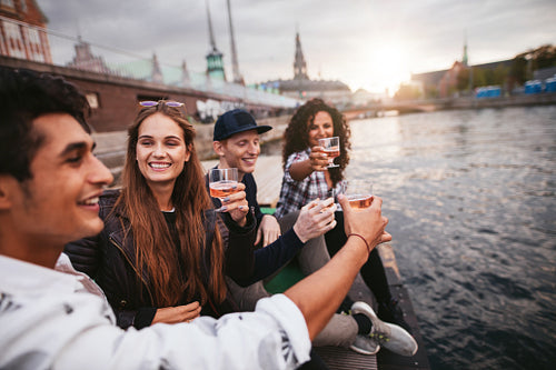 Group of friends hanging out by the lake with drinks