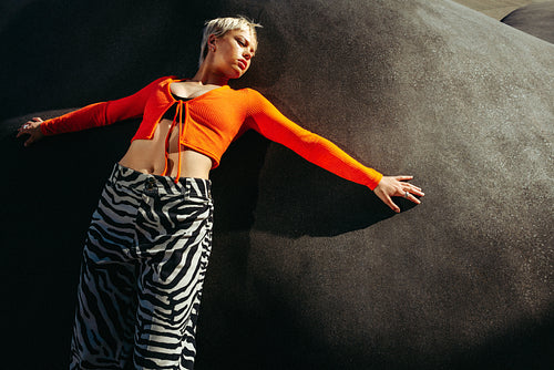 Woman poses in outdoor fashion portrait against a dark architectural surface