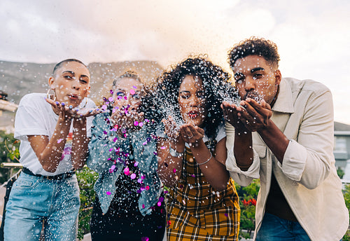 Group of friends blowing confetti during a party