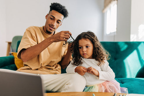 Modern dad styling his daughter's hair using an online tutorial