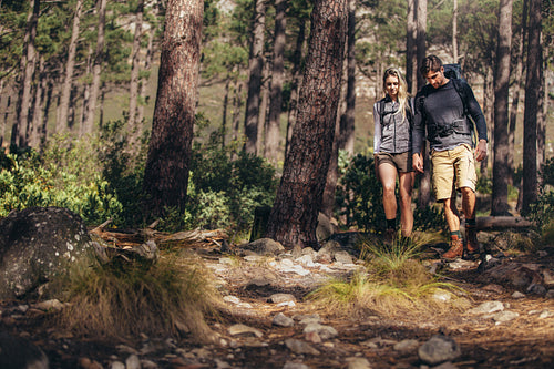 Hiking couple walking on rocks in forest wearing backpacks