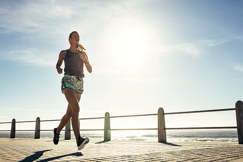 Fitness young woman jogging along the beach