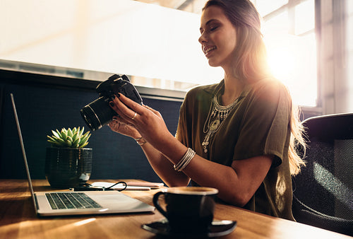 Young female vlogger watching her camera while editing her vlog on computer.
