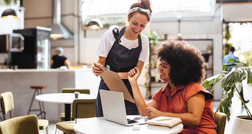 Restaurant service: Happy woman reading the menu from the waitress