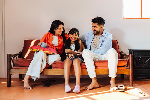 Smiling family relaxing together on a cozy sofa in a bright living room