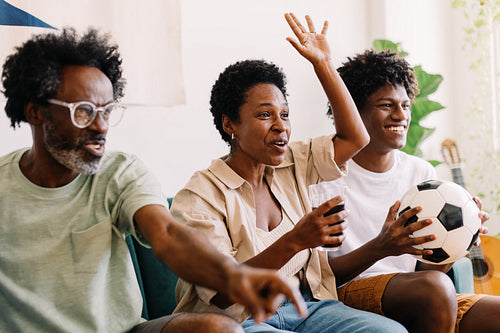 Family cheering while watching a football game on tv at home