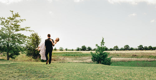 Groom carrying the bride at park
