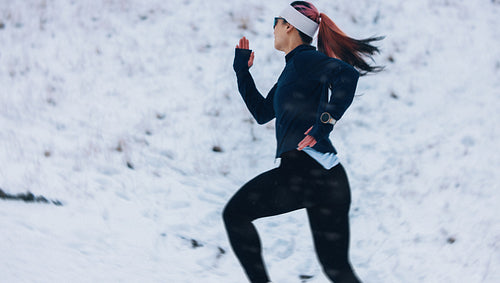 Strength in running helps the woman push through winter snow outdoors