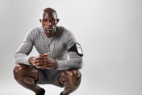 Young african man crouching on grey background