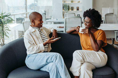 Business colleagues having a coffee break and discussing work on the office sofa
