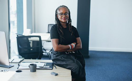 Portrait of a black and mature business woman sitting on her office desk