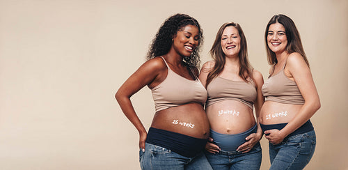 Multicultural group of happy expecting mothers smiling in studio