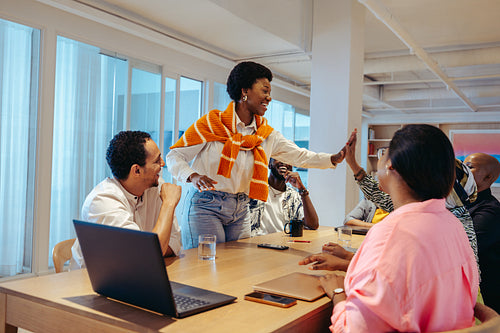 Team celebrating success in a modern agency office with a high-five