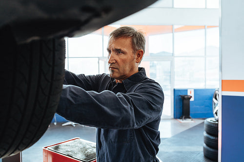 Mechanic changing wheel of a car in service station