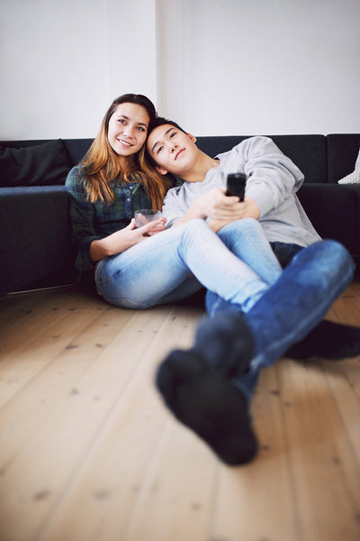 Relaxed teenage couple watching TV at home