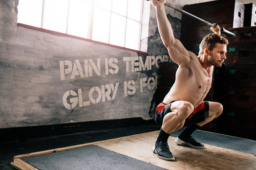 Fit man at crossfit gym lifting barbell