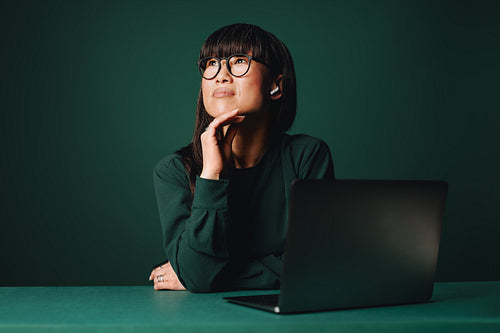 Planning work, the woman focuses on her laptop in a studio office setting