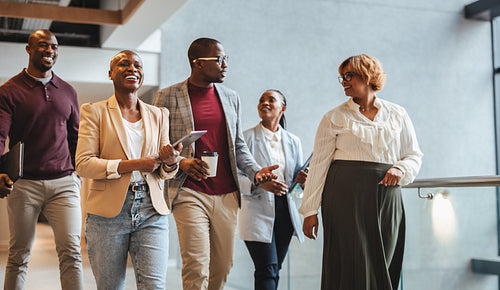Group of business professionals walking and talking in a modern office environment
