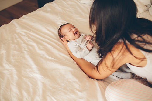 Smiling little boy lying on bed with his mother