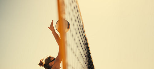 Pro athlete spiking ball in panoramic coastal game play at summer beach tournament