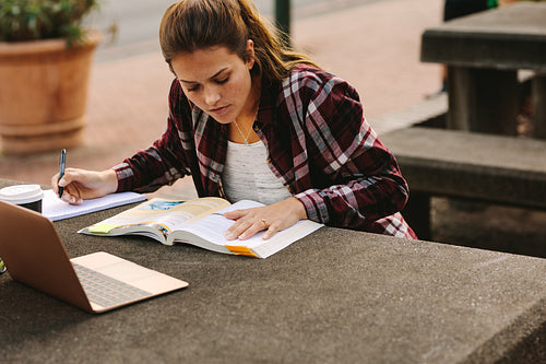 Female student making notes at college campus