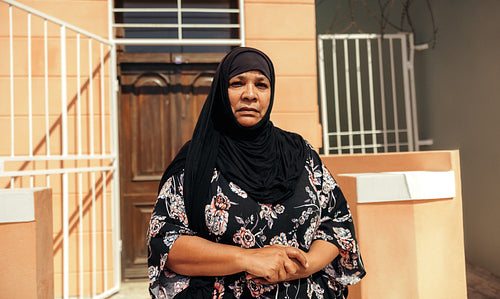 Self-confident Muslim woman looking at the camera outside her home