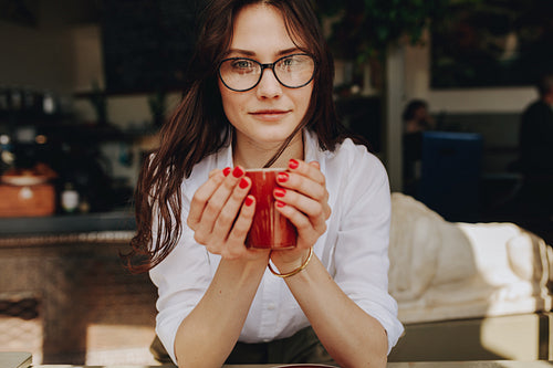 Woman at cafe holding a cup of coffee 