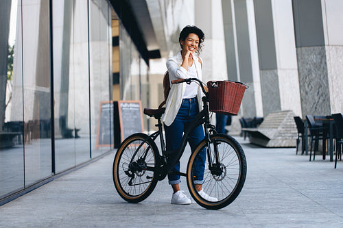 Happy woman posing with a bicycle in an urban European city setting