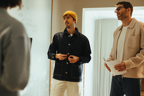 Coworkers discuss ideas at the whiteboard during office brainstorming