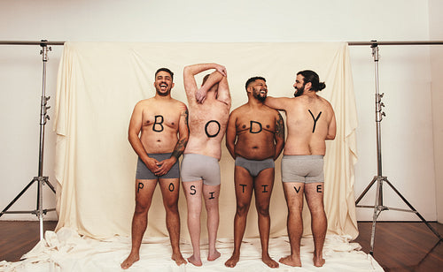 Body positive men standing shirtless in a studio