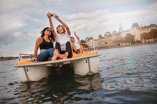 Young friends taking selfie on pedal boat