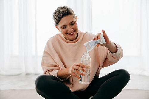 Hydration comes first as the woman mixes a supplement after workout at home