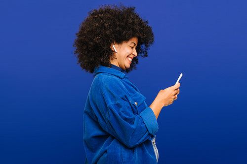 Carefree young woman playing music using a smartphone and earbuds