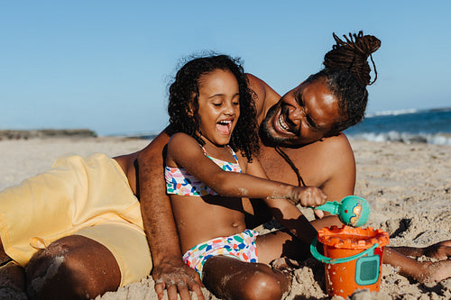 Father and daughter enjoying a fun beach vacation, playing in the sand together