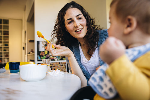 Caring mother feeding toddler while on maternity leave